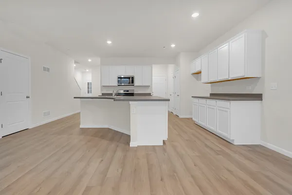 a kitchen with wooden floors and white cabinets