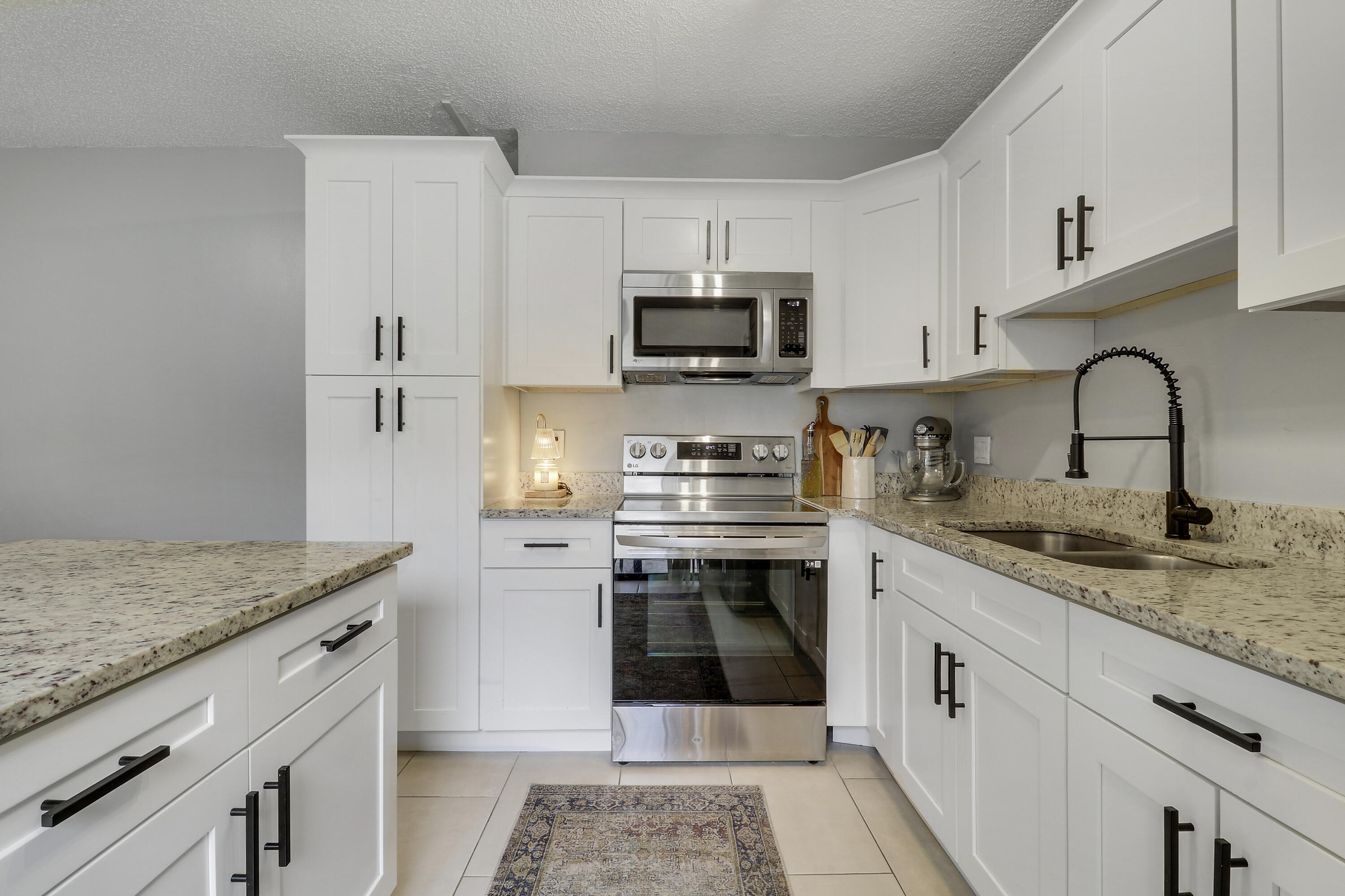 187 Woodland Road Palm Springs, FL 33461 - Photo 7 of 29 a kitchen with granite countertop a sink stainless steel appliances and white cabinets