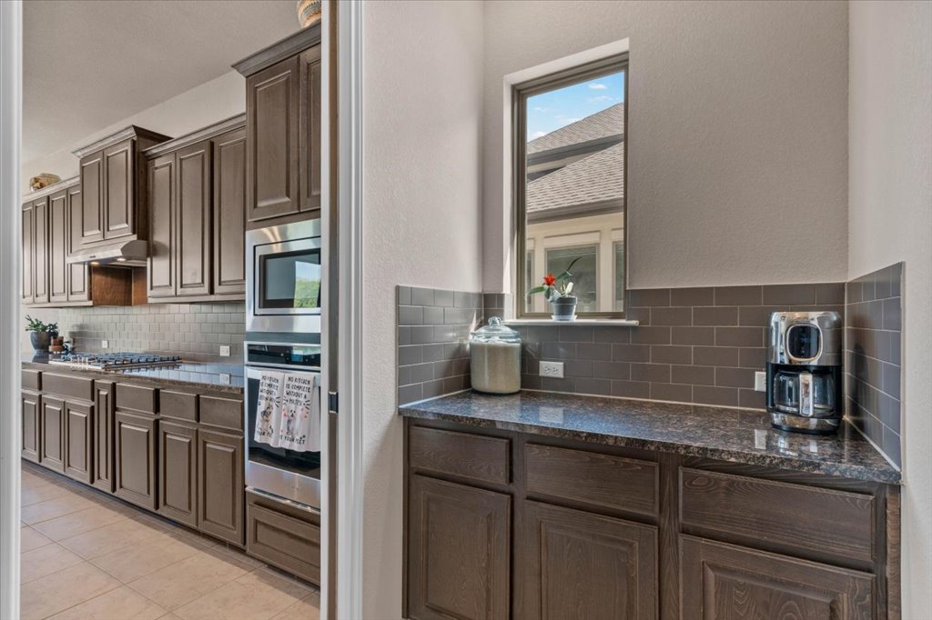 6705 Destination Way Jonestown, TX 78645 - Photo 13 of 39 This dedicated coffee station and prep area features rich espresso cabinetry, sleek granite countertops, and a modern subway tile backsplash—perfect for keeping the main kitchen clutter-free while you brew your morning espresso.