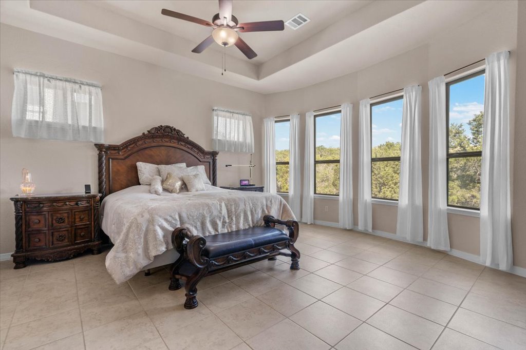 6705 Destination Way Jonestown, TX 78645 - Photo 15 of 39 Rest and relaxation meet elegance in this expansive primary suite. The tray ceiling adds architectural depth, while a wall of oversized windows invites the outside in.