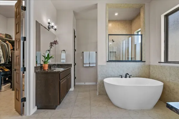a bathroom with a granite countertop sink and mirror with bathtub
