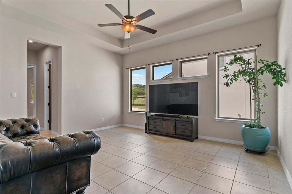 6705 Destination Way Jonestown, TX 78645 - Photo 24 of 39 Keep things cool and airy in this versatile secondary living space. With neutral tile, a sleek tray ceiling, and large windows, it’s the perfect spot for a media room or a quiet afternoon lounge.