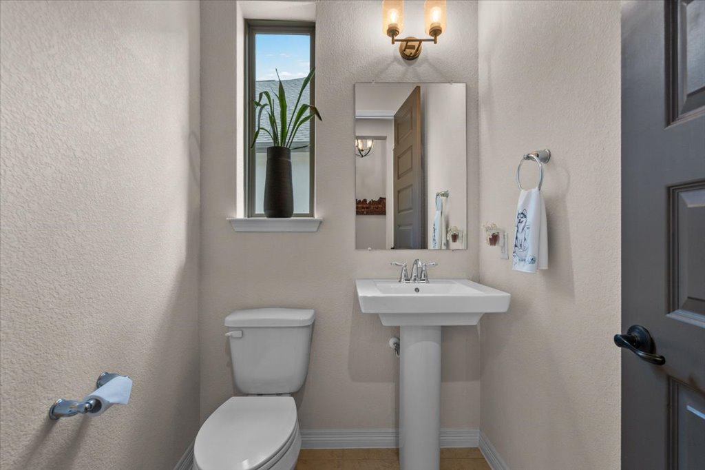 6705 Destination Way Jonestown, TX 78645 - Photo 25 of 39 Even the powder room gets the VIP treatment. A classic pedestal sink and a tall, narrow window create a bright, chic space for guests, finished with modern fixtures.