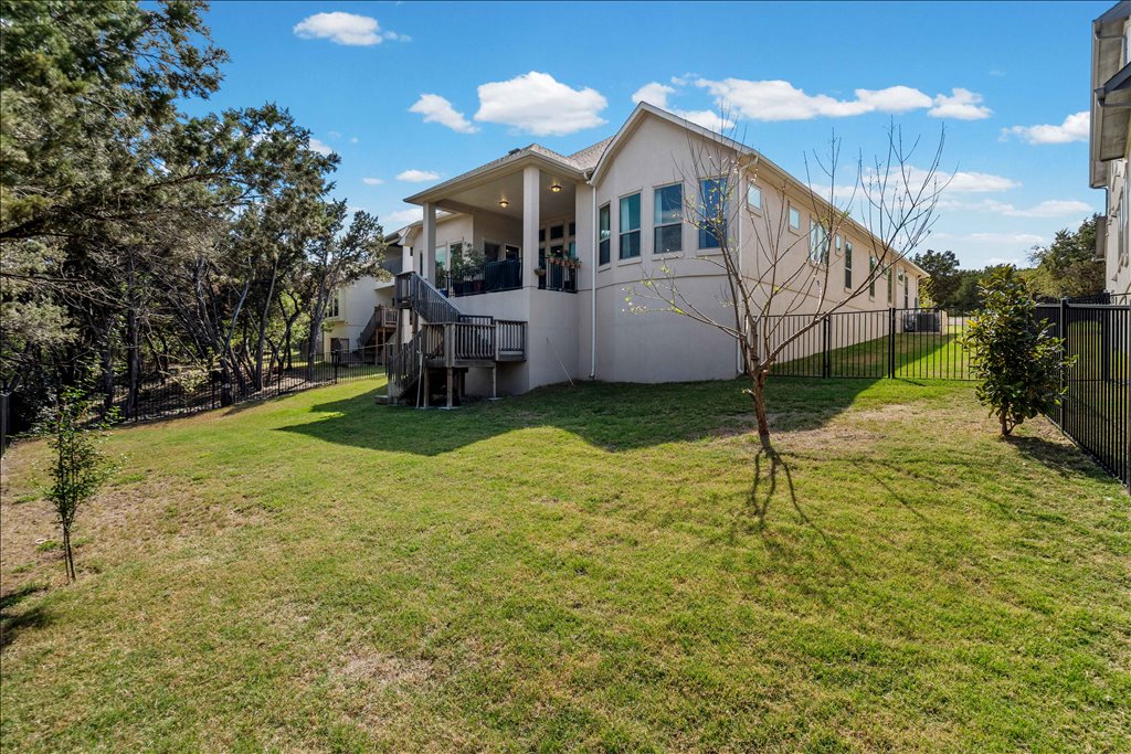 6705 Destination Way Jonestown, TX 78645 - Photo 27 of 39 A private, fenced oasis with plenty of room to roam. The manicured lawn slopes gently toward the tree line, offering a perfect balance of open space for play and natural wooded privacy at the rear of the property.