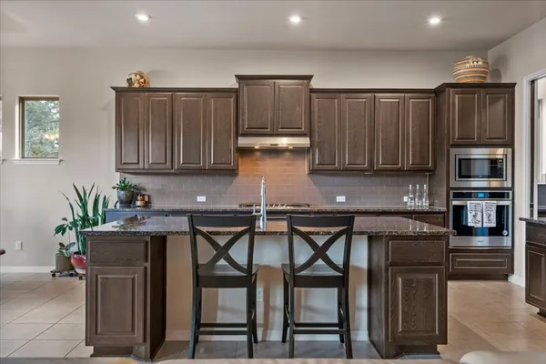 a kitchen with kitchen island granite countertop stainless steel appliances a refrigerator a stove a sink a center island and a refrigerator