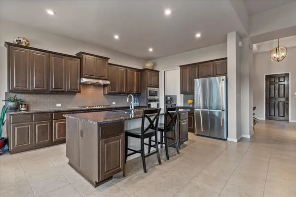 a kitchen with kitchen island granite countertop wooden cabinets and stainless steel appliances