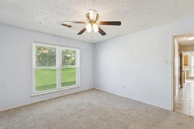 an empty room with windows and fan