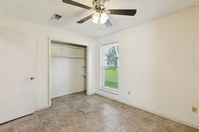 an empty room with chandelier fan and windows