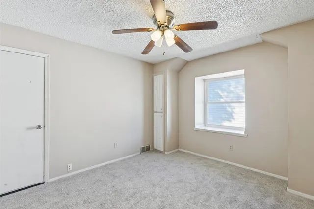 an empty room with windows and fan