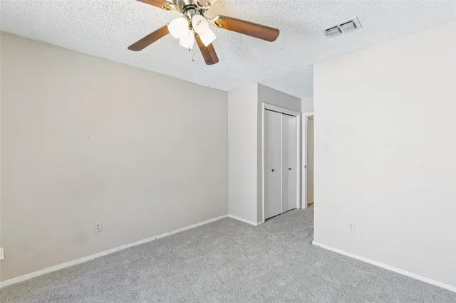 an empty room with closet and a chandelier fan