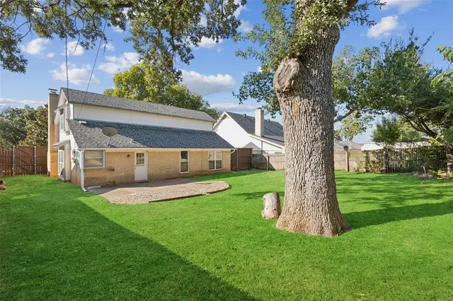 a view of a house with a yard and a large tree