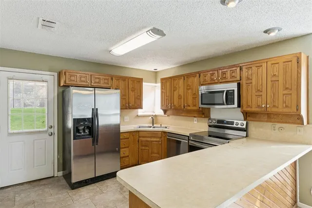 a kitchen with stainless steel appliances a stove a refrigerator a sink a oven with white cabinets and wooden floor