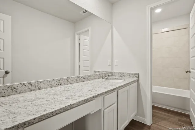 a bathroom with a granite countertop sink and a bathtub