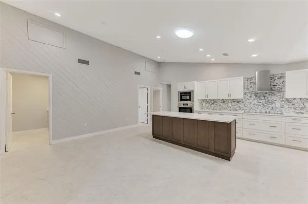 a large kitchen with stainless steel appliances a large counter top a stove a sink a refrigerator and white cabinets