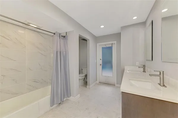 a bathroom with a granite countertop sink a mirror and a bathtub