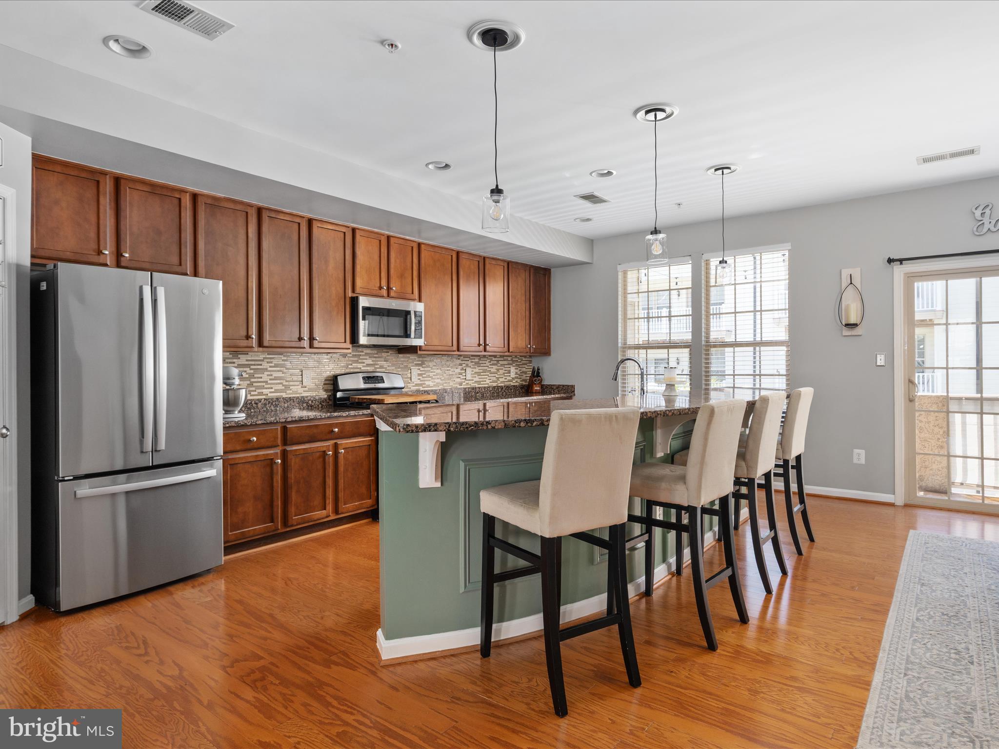 7734 Cedar Branch Drive Gainesville, VA 20155 - Photo 12 of 62 a kitchen with stainless steel appliances granite countertop a dining table chairs refrigerator and microwave