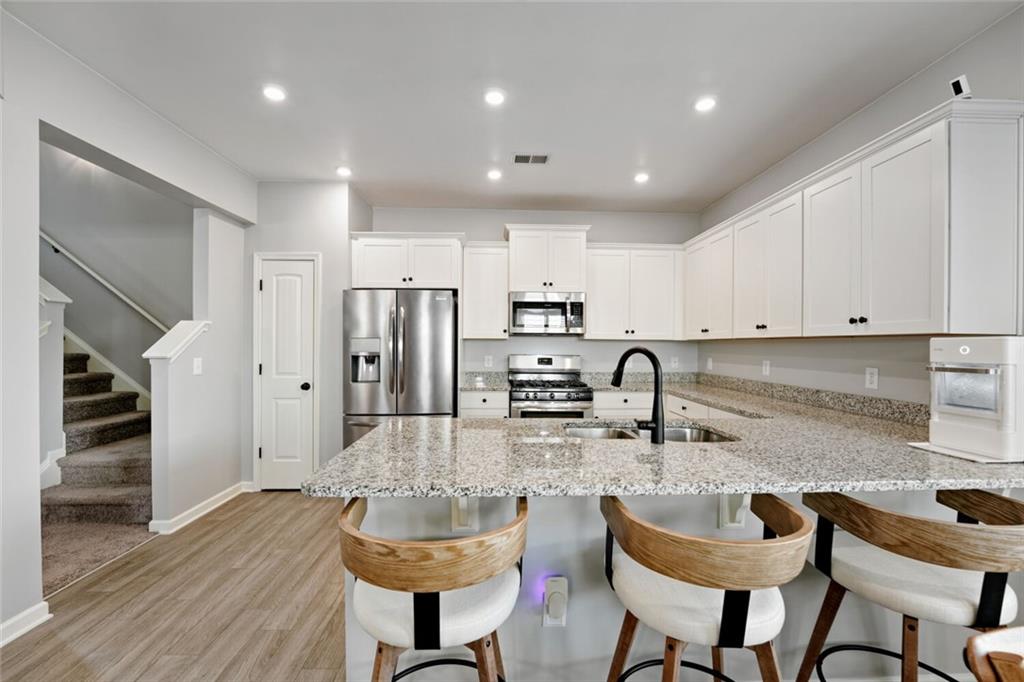 153 Bryon Lane Acworth, GA 30102 - Photo 15 of 25 a kitchen with stainless steel appliances granite countertop a stove a sink a refrigerator and white cabinets with wooden floor