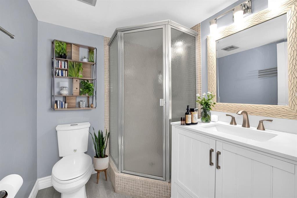 9355 Southwest 8th Street, Unit 401 Boca Raton, FL 33428 - Photo 13 of 37 a bathroom with a toilet sink and mirror