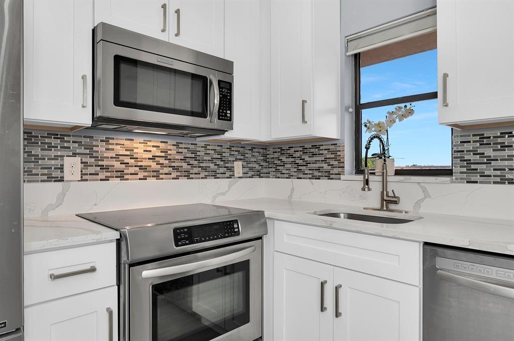 9355 Southwest 8th Street, Unit 401 Boca Raton, FL 33428 - Photo 7 of 37 a kitchen with granite countertop a sink stove and microwave