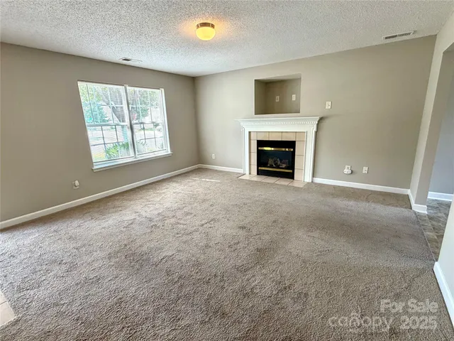 a view of an empty room with a window and fireplace