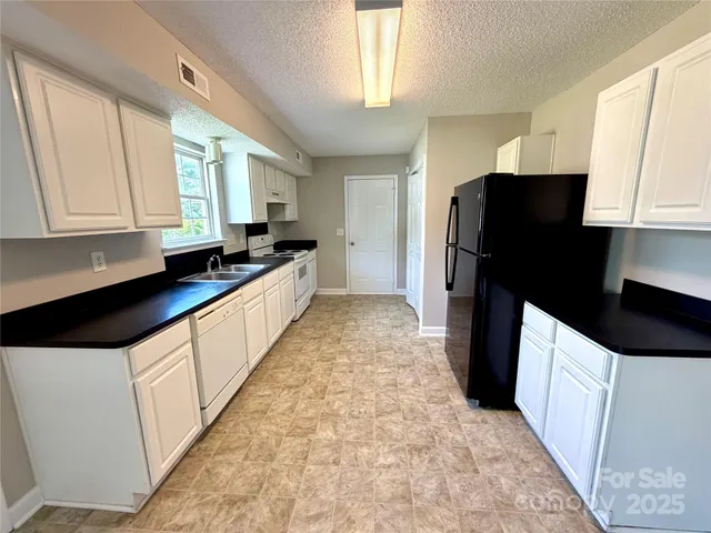 a kitchen with granite countertop a refrigerator and a sink