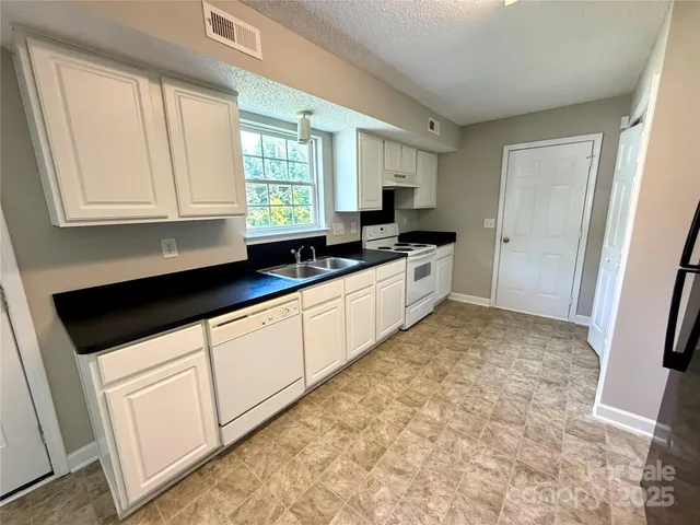 a kitchen with granite countertop a sink a stove and cabinets