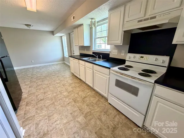 a kitchen with granite countertop a stove a sink and a microwave