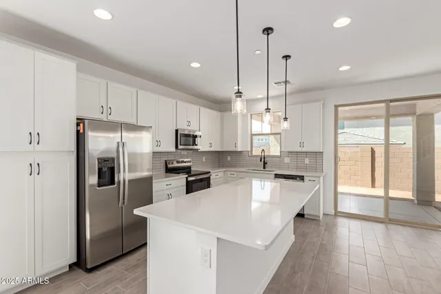 a kitchen with refrigerator a stove a sink a center island and furniture