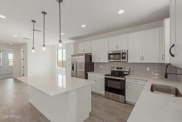 a kitchen with stainless steel appliances granite countertop a sink a stove a refrigerator and cabinets