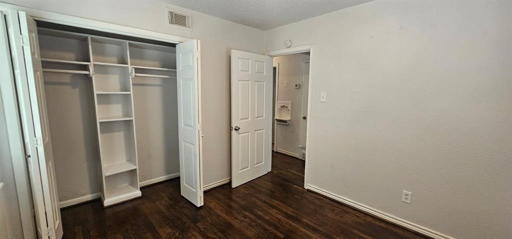 5170 Cardiff Street Dallas, TX 75241 - Photo 13 of 14 Unfurnished bedroom with dark wood finished floors, a closet, baseboards, and a textured ceiling