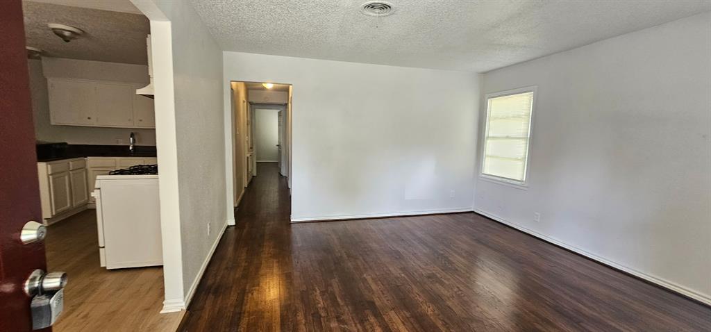 5170 Cardiff Street Dallas, TX 75241 - Photo 5 of 14 Spare room featuring dark wood finished floors, a textured ceiling, and baseboards
