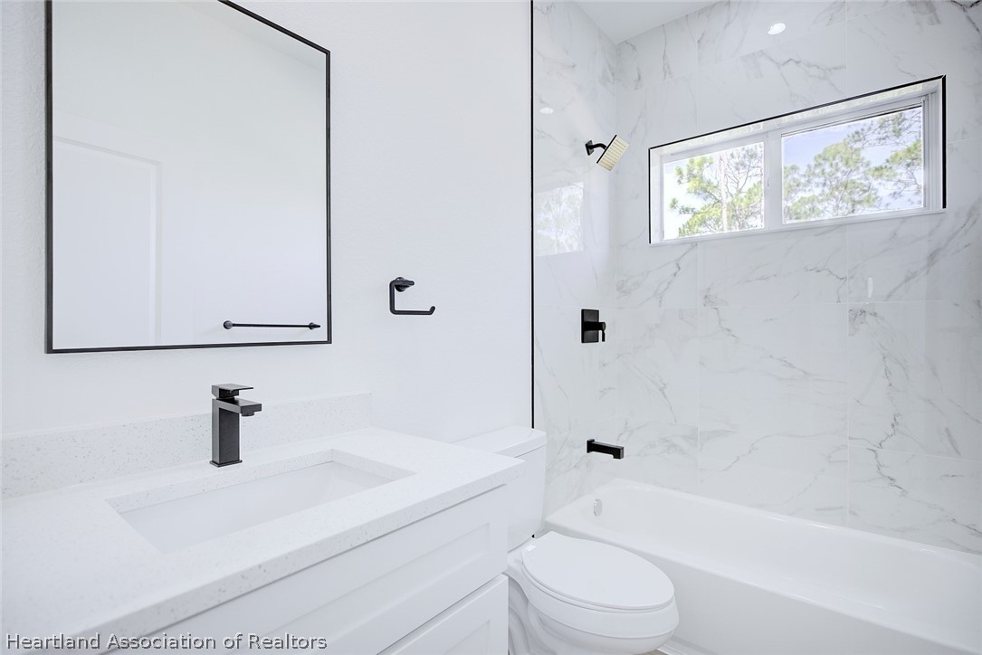 4307 Talbot Street Sebring, FL 33872 - Photo 13 of 19 a bathroom with a toilet a sink a mirror and shower
