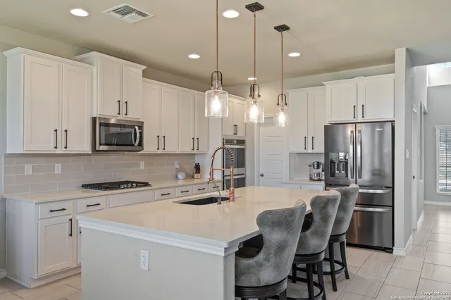 a kitchen with stainless steel appliances a stove a sink island and a refrigerator