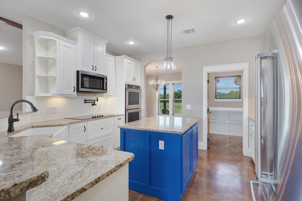 516 Springtown Road Van Alstyne, TX 75495 - Photo 15 of 40 a kitchen with kitchen island granite countertop a sink stainless steel appliances and cabinets