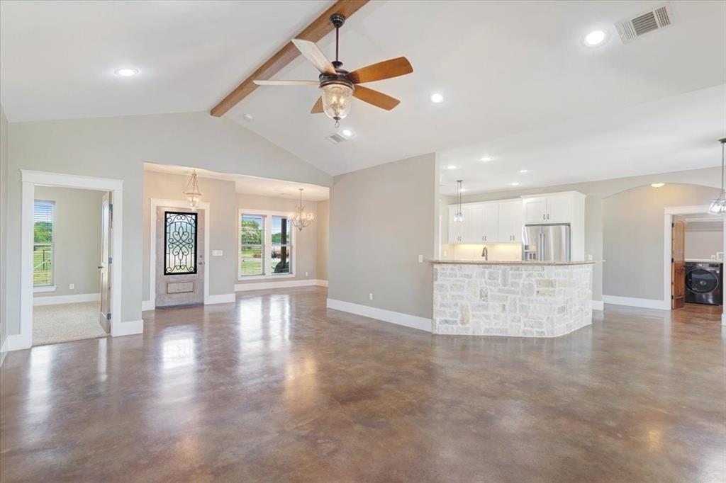 516 Springtown Road Van Alstyne, TX 75495 - Photo 10 of 40 a view of an empty room and kitchen with wooden floor and a ceiling fan