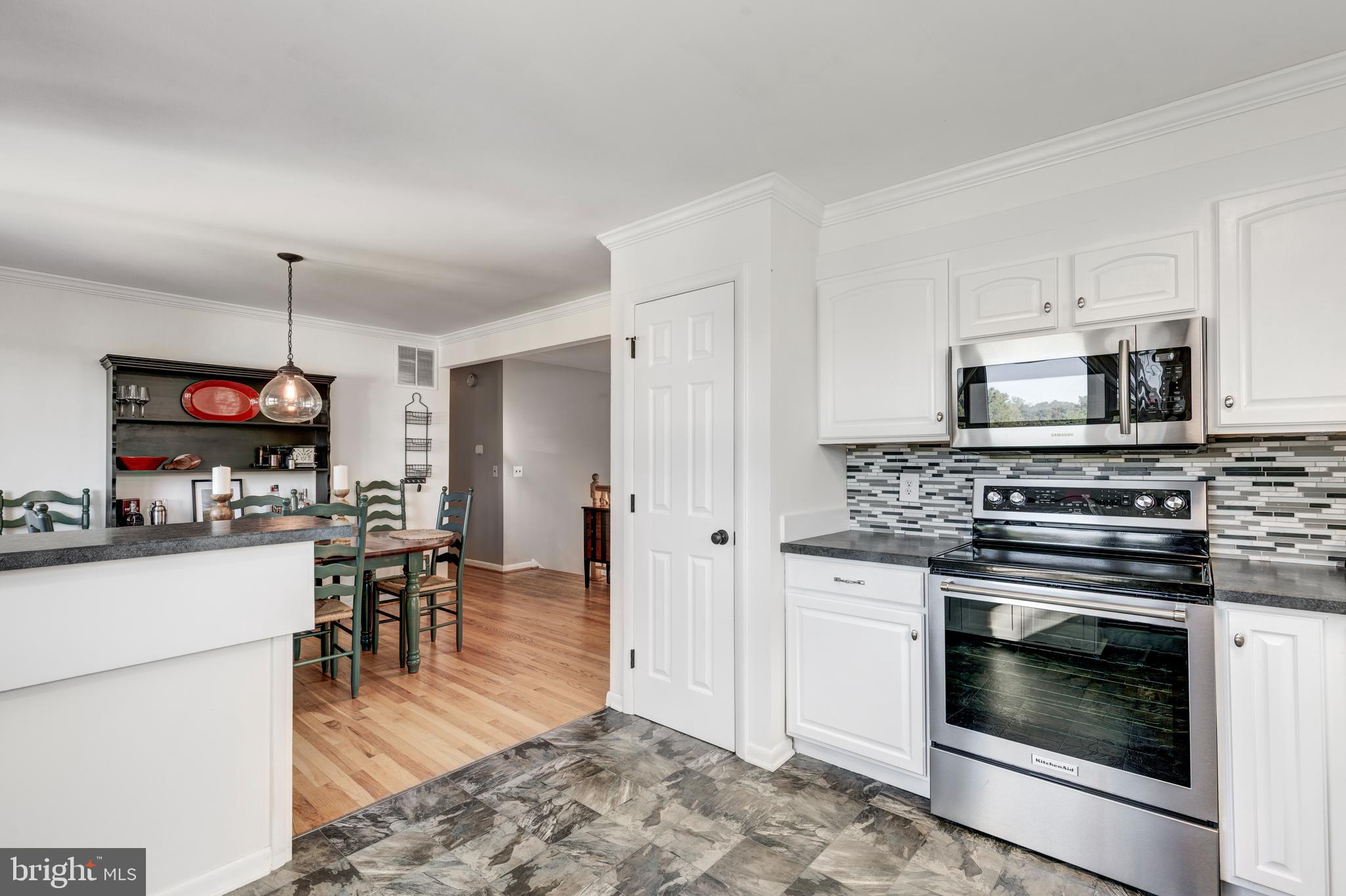 2108 Hanover Pike Hampstead, MD 21074 - Photo 7 of 51 a kitchen with stainless steel appliances kitchen island granite countertop a stove top oven a sink a dining table and chairs with wooden floor