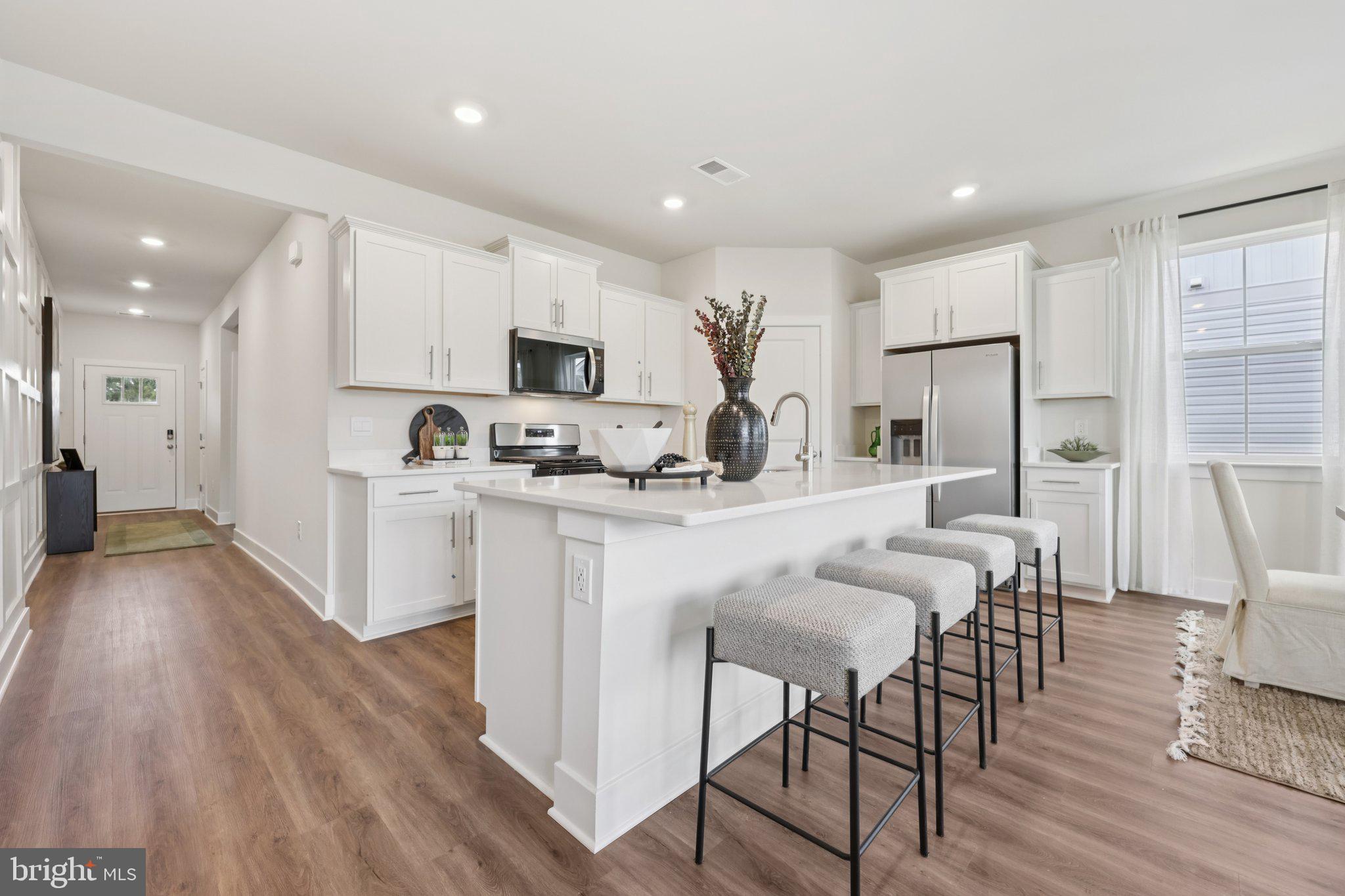 110 Trellis View Lane Winchester, VA 22602 - Photo 13 of 45 a kitchen with stainless steel appliances kitchen island granite countertop a refrigerator a stove a sink a dining table and chairs with wooden floor