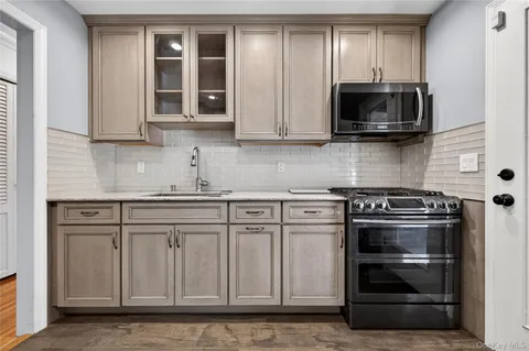 a kitchen with stainless steel appliances granite countertop white cabinets and a stove top oven