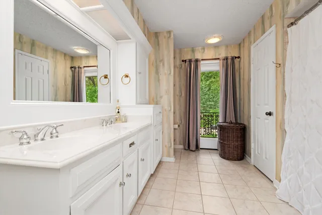 a bathroom with a double vanity sink a large mirror and a bathtub