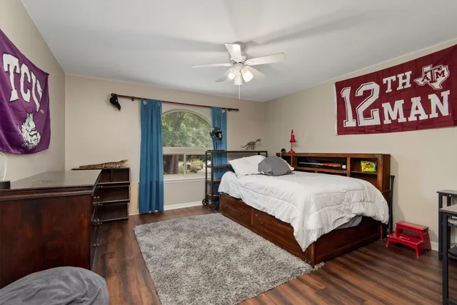 a bedroom with a bed and a dresser with wooden floor