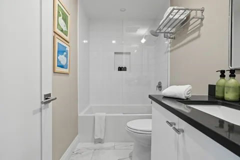 a bathroom with a granite countertop sink a toilet and shower