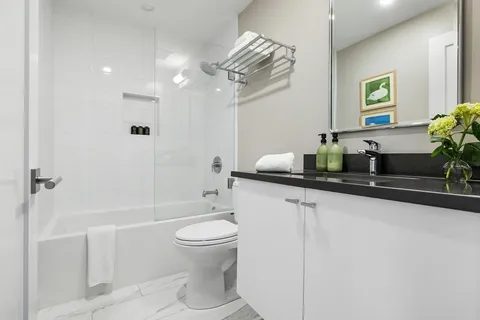 a bathroom with a granite countertop sink a toilet a mirror and shower