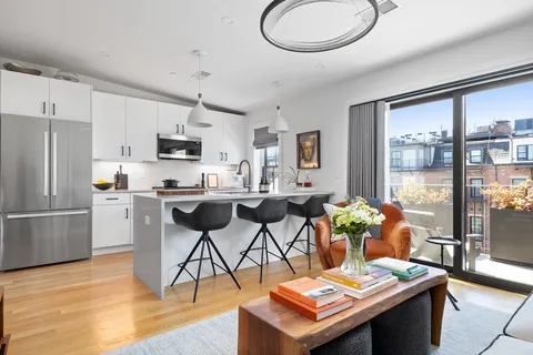 a open kitchen with stainless steel appliances granite countertop a stove top oven a sink dishwasher a dining table and chairs with wooden floor