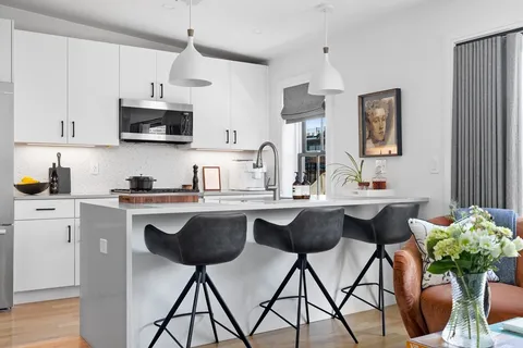 a kitchen with stainless steel appliances a sink a stove a kitchen island with chairs and cabinets