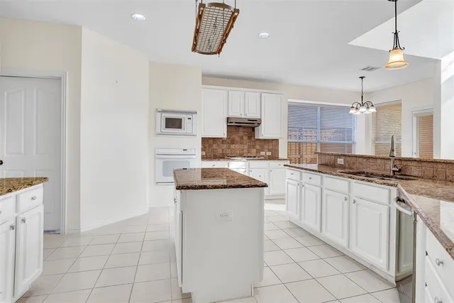a kitchen with granite countertop a sink a counter top space appliances and cabinets