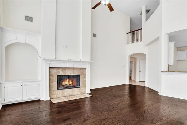 a view of an empty room with wooden floor and fireplace