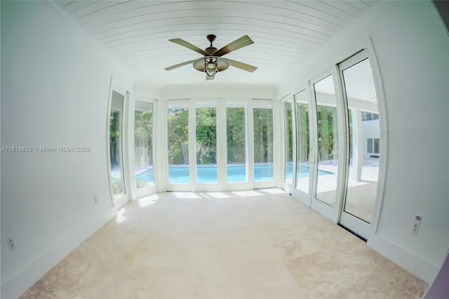 a view of an empty room with a ceiling fan and windows