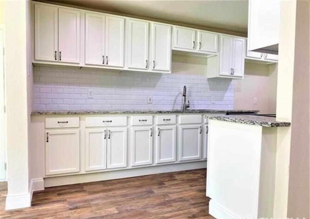 2536 Rutherford Street Irving, TX 75062 - Photo 5 of 19 Kitchen featuring white shaker cabinetry, speckled countertops, a white subway tile backsplash, a stainless steel faucet, and wood-finish flooring