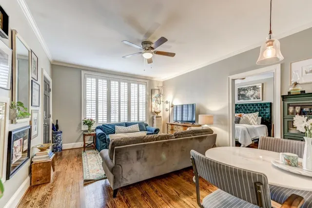 a living room with two couches a table and chairs with wooden floor