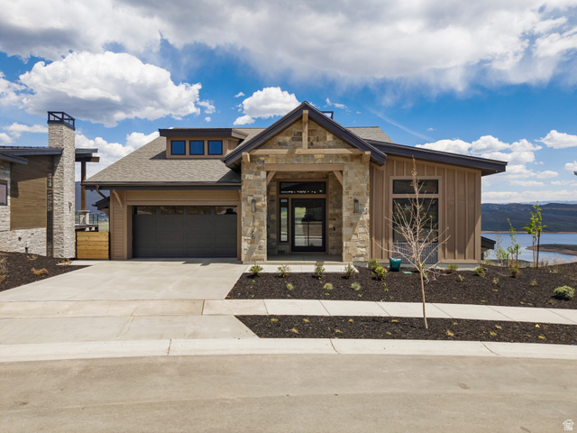 11366 North Regal Rdg Court, Unit 8 Heber City, UT 84032 - Photo 1 of 1 Modern mountain-style residence featuring stone and vertical wood siding, an attached garage, a contemporary entry door, a prominent stone chimney, and a concrete driveway